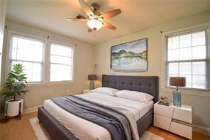 bedroom featuring multiple windows, hardwood / wood-style floors, and ceiling fan