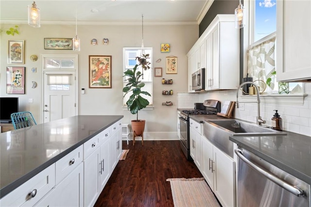 kitchen with sink, white cabinetry, appliances with stainless steel finishes, ornamental molding, and pendant lighting