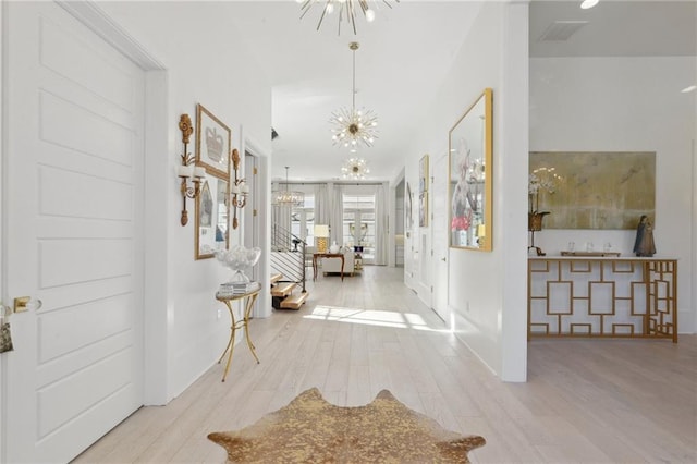 hall with an inviting chandelier and light wood-type flooring