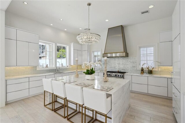 kitchen with premium range hood, stainless steel range, a kitchen island, and white cabinets