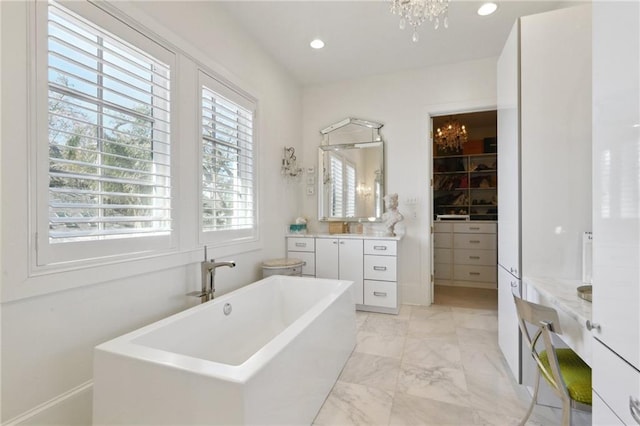 bathroom with vanity, a chandelier, and a tub