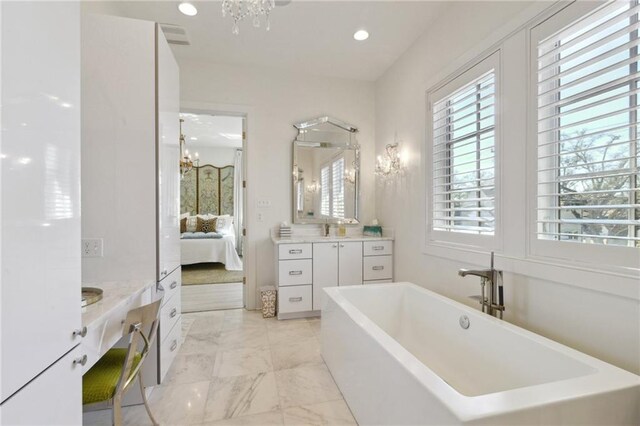 bathroom with an inviting chandelier, vanity, and a bath