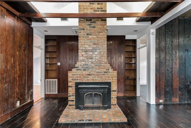 unfurnished living room featuring beam ceiling, built in features, and wood walls