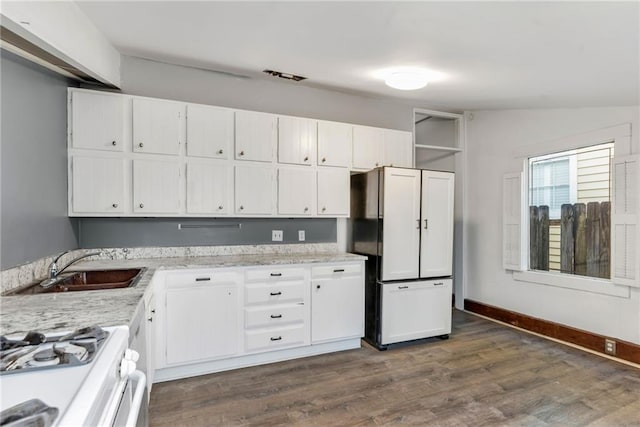 kitchen with sink, gas range gas stove, paneled refrigerator, white cabinets, and dark hardwood / wood-style flooring