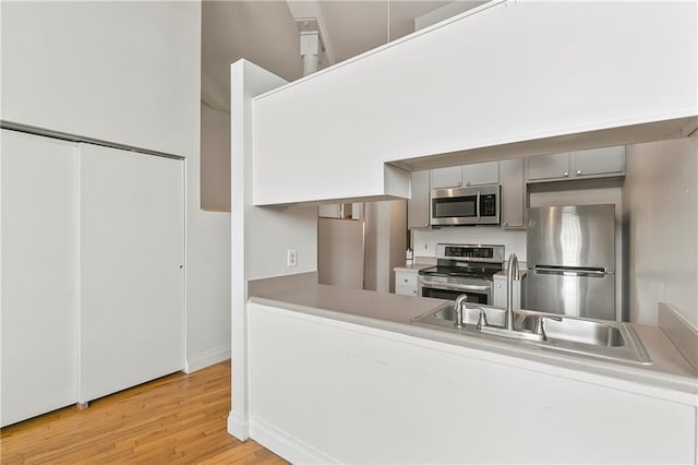 kitchen featuring stainless steel appliances, sink, light hardwood / wood-style flooring, and gray cabinetry