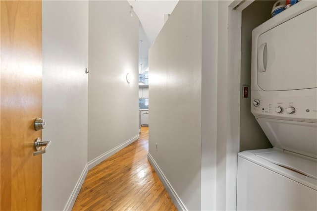 laundry room featuring stacked washer and clothes dryer and light hardwood / wood-style flooring