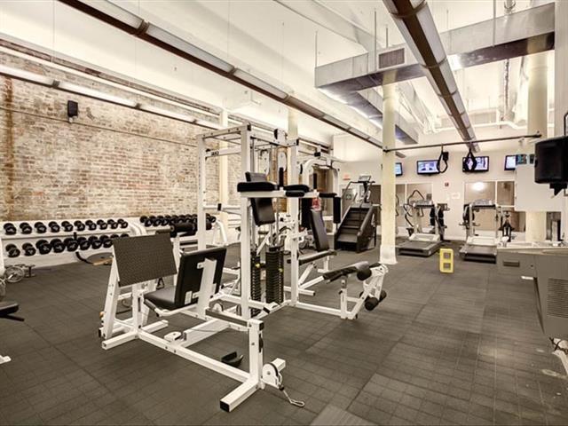 exercise room featuring a towering ceiling and brick wall