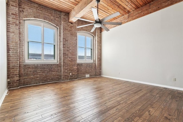 empty room featuring wood ceiling, hardwood / wood-style flooring, beamed ceiling, ceiling fan, and brick wall