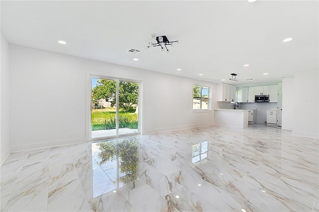 unfurnished living room featuring recessed lighting and marble finish floor