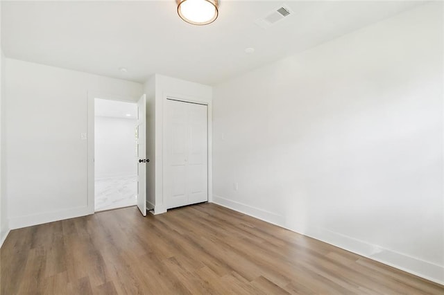 spare room with visible vents, baseboards, and wood finished floors