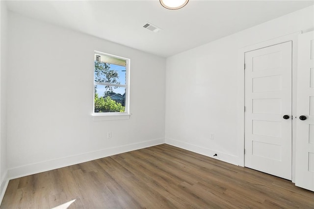 spare room with visible vents, baseboards, and wood finished floors