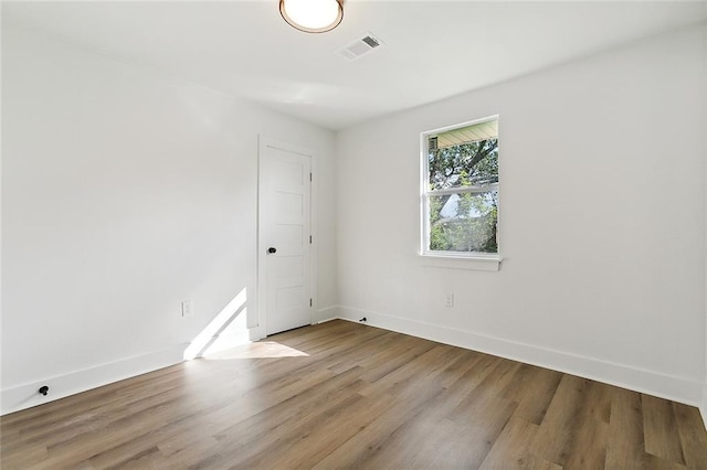 unfurnished room with wood finished floors, baseboards, and visible vents