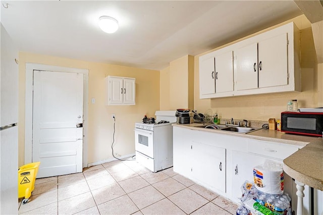 kitchen with light tile patterned flooring, sink, white gas stove, and white cabinets