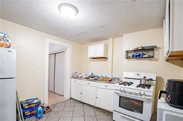 kitchen with white appliances, sink, a textured ceiling, and white cabinets