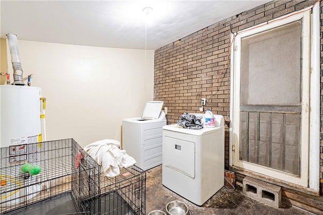 clothes washing area with brick wall, water heater, and washer and dryer