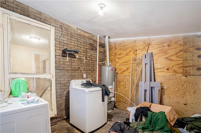 clothes washing area featuring separate washer and dryer, water heater, and brick wall