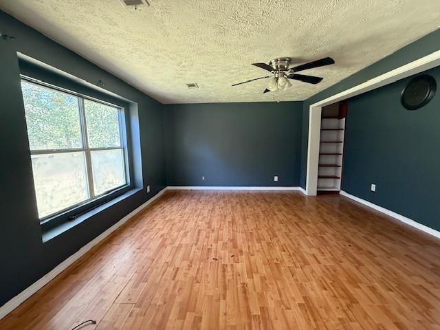 empty room featuring wood-type flooring, ceiling fan, and a textured ceiling