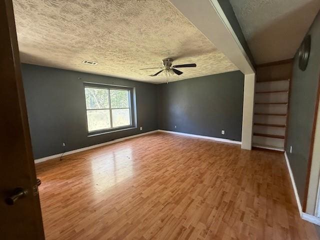 empty room with wood-type flooring, ceiling fan, and a textured ceiling