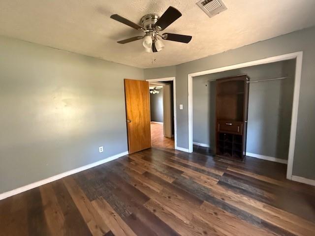 unfurnished bedroom with dark hardwood / wood-style flooring, ceiling fan, and a closet