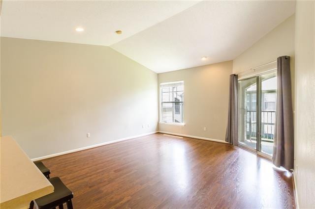 spare room featuring dark hardwood / wood-style flooring, plenty of natural light, and vaulted ceiling