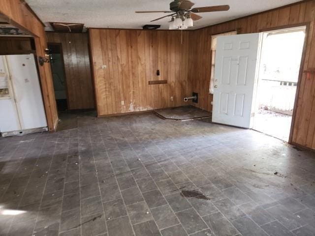 empty room with ceiling fan and wooden walls