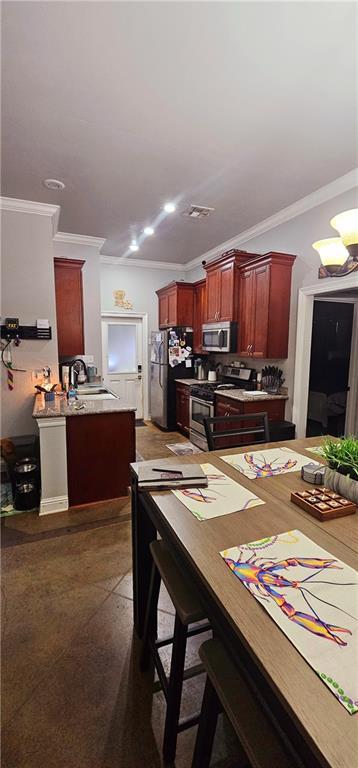 kitchen with crown molding, appliances with stainless steel finishes, a kitchen breakfast bar, and sink