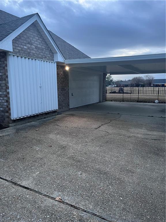 2261 Country Club Dr, La Place, LA 70068 - garage with driveway, a carport, and fence