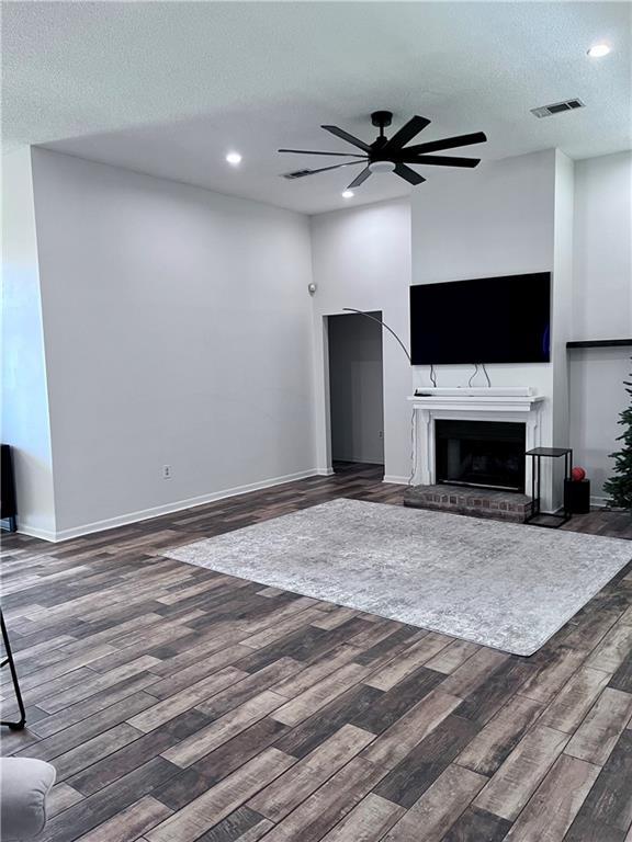 2261 Country Club Dr, La Place, LA 70068 - unfurnished living room featuring a ceiling fan, wood finished floors, a brick fireplace, a textured ceiling, and visible vents