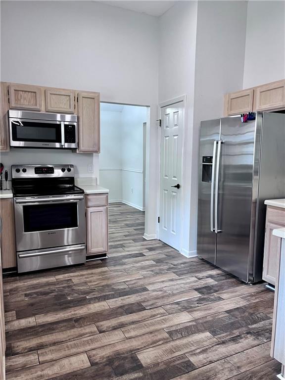 2261 Country Club Dr, La Place, LA 70068 - kitchen featuring light countertops, a towering ceiling, dark wood-type flooring, and stainless steel appliances
