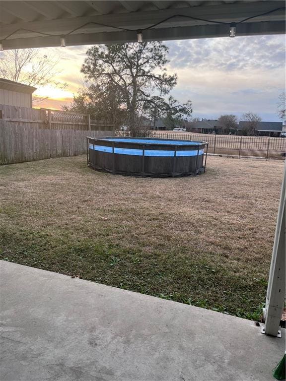 yard at dusk featuring a fenced in pool and a patio