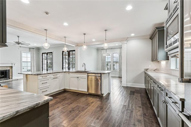 kitchen with white cabinetry, hanging light fixtures, light stone counters, and appliances with stainless steel finishes