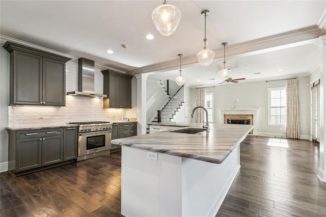 kitchen with dark hardwood / wood-style floors, pendant lighting, sink, high end range, and wall chimney exhaust hood