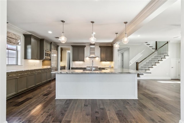 kitchen featuring crown molding, pendant lighting, stainless steel microwave, and wall chimney exhaust hood