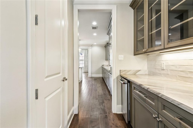 kitchen featuring crown molding, tasteful backsplash, dark brown cabinets, dark hardwood / wood-style floors, and light stone countertops