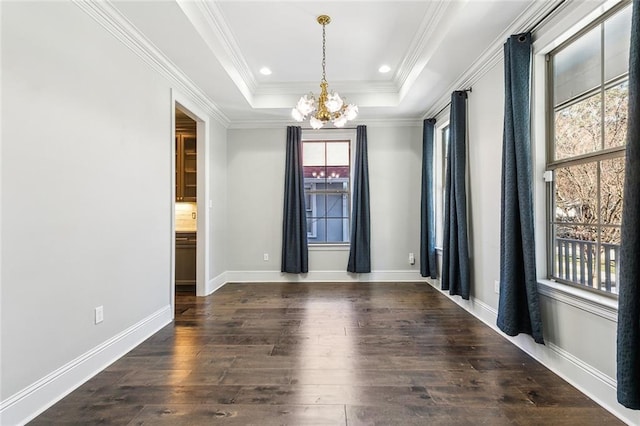 empty room with dark wood-type flooring, a tray ceiling, a chandelier, and crown molding