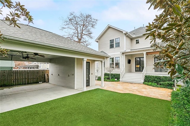 back of property featuring a carport, a porch, ceiling fan, and a lawn