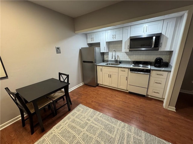 kitchen with sink, stainless steel appliances, dark hardwood / wood-style floors, tasteful backsplash, and white cabinets