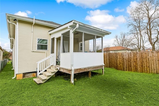 back of house with a sunroom and a lawn