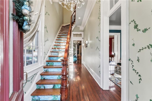 foyer entrance featuring ornamental molding, dark wood-type flooring, and an inviting chandelier