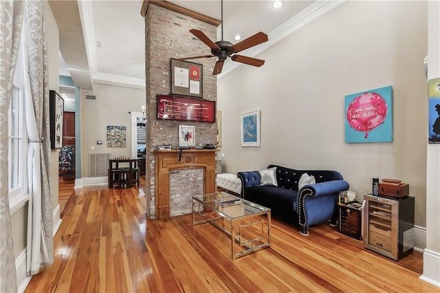 living room with hardwood / wood-style floors, crown molding, and ceiling fan