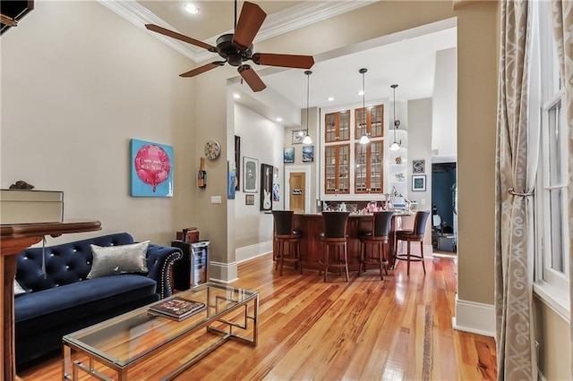 living room featuring ornamental molding, indoor bar, ceiling fan, and light hardwood / wood-style flooring