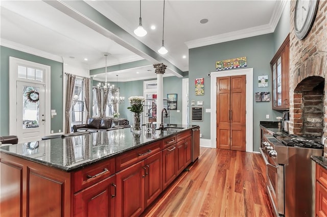 kitchen with sink, decorative light fixtures, appliances with stainless steel finishes, an island with sink, and dark stone counters