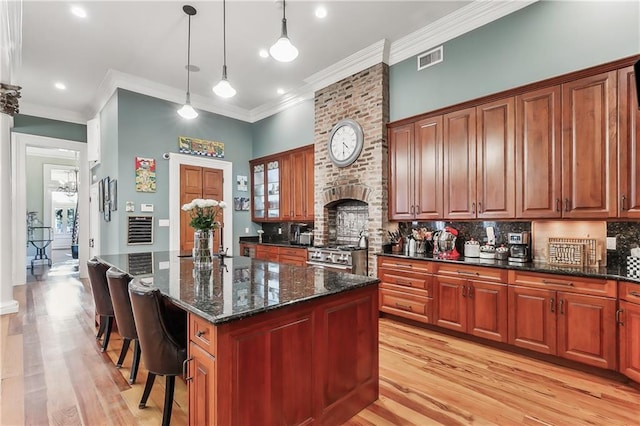 kitchen with a kitchen bar, hanging light fixtures, a kitchen island, high end stainless steel range oven, and backsplash