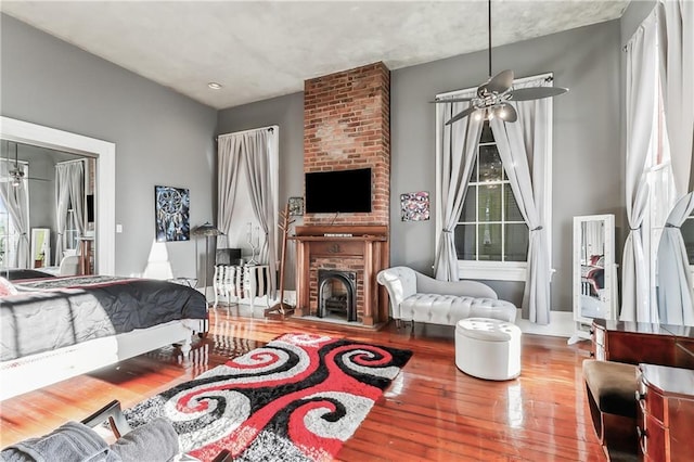 bedroom with hardwood / wood-style flooring, a fireplace, and multiple windows