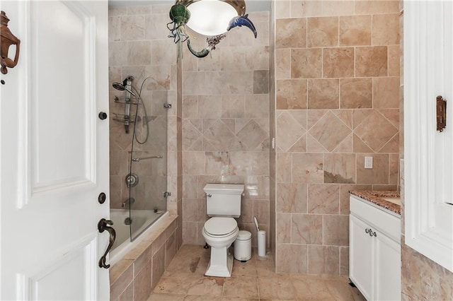 full bathroom featuring vanity, tiled shower / bath combo, toilet, and tile walls