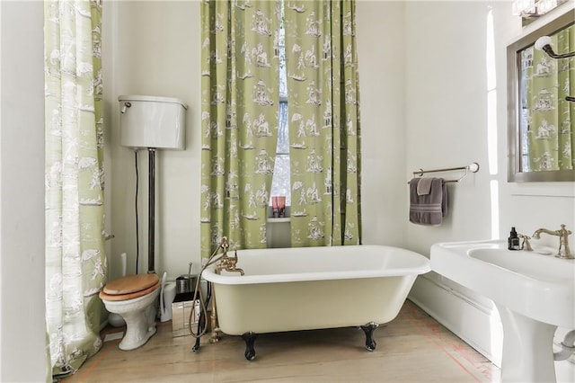 bathroom with wood-type flooring, toilet, sink, and a washtub