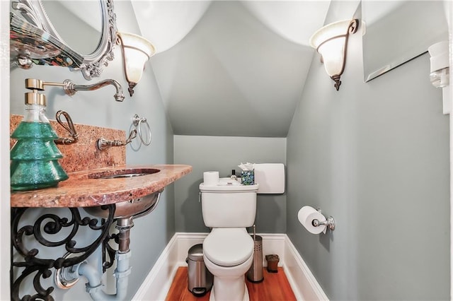 bathroom featuring wood-type flooring, lofted ceiling, and toilet