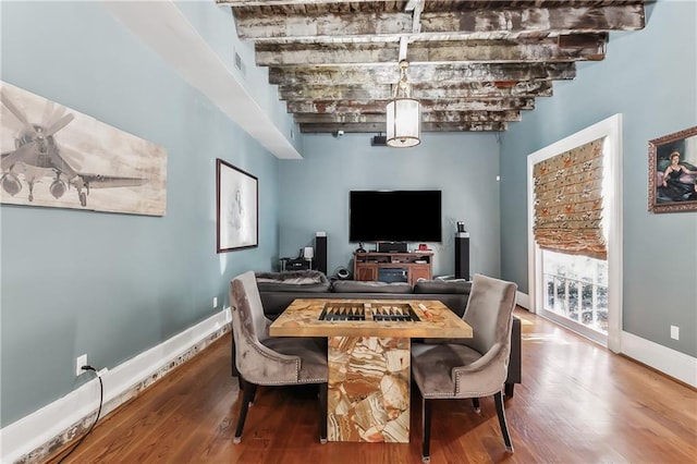 dining space with beam ceiling and hardwood / wood-style flooring