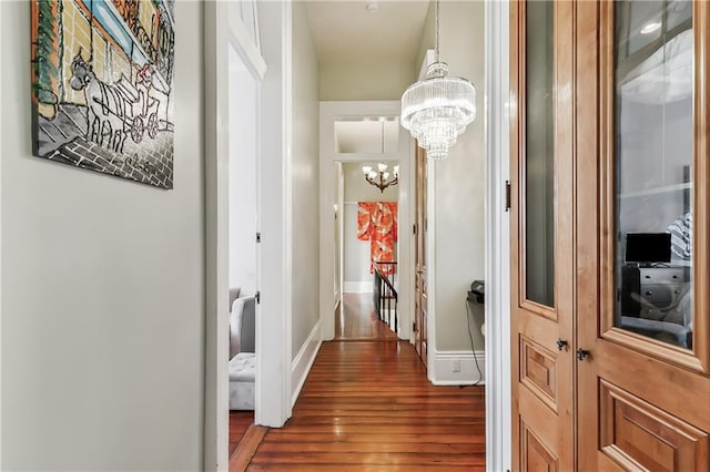 hallway featuring an inviting chandelier and dark hardwood / wood-style flooring