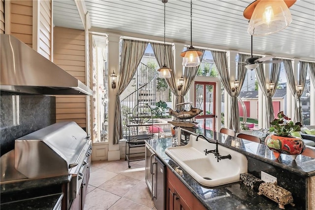 kitchen featuring dark stone countertops, sink, pendant lighting, and light tile patterned floors